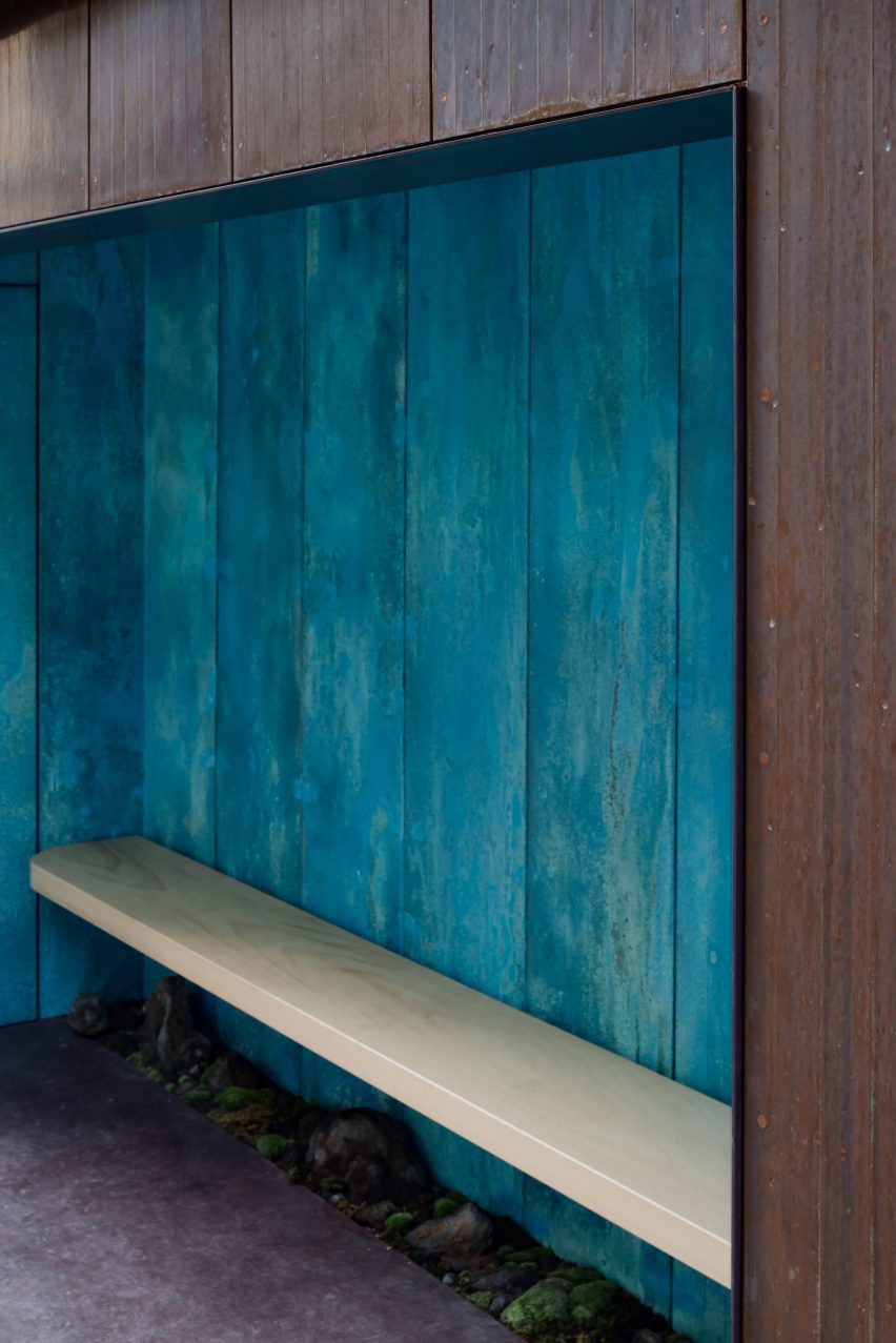 Wooden bench against a blue copper wall