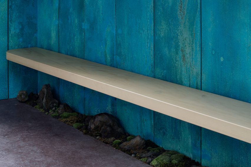 Wooden bench against a blue copper wall