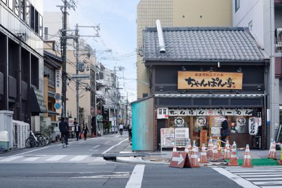 Blue oxidised copper kiosk next to a black timber building in Kyoto