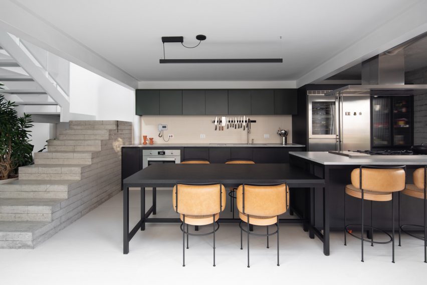 Open-plan kitchen with concrete staircase at Casa Yuji in Sao Paulo by Goiva