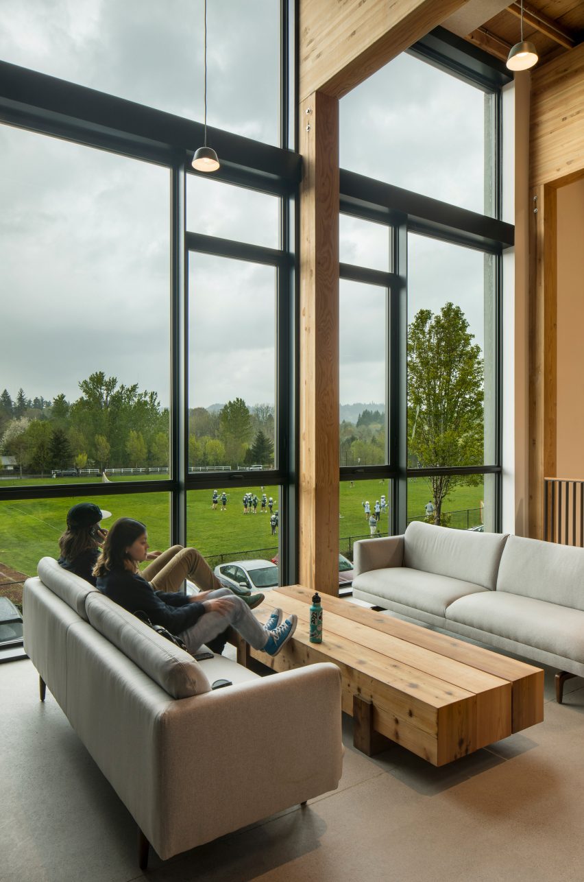 A timber study space with grey sofas beside a large window