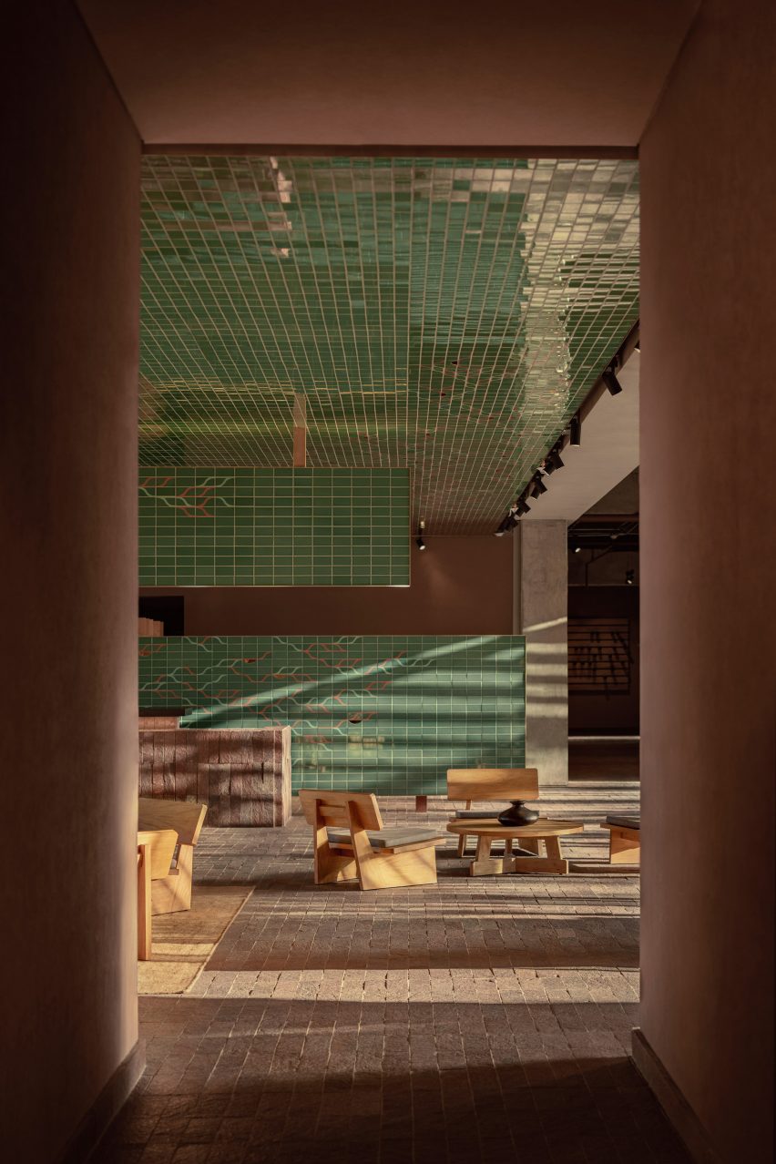A hotel lobby with green tiling and a stone floor
