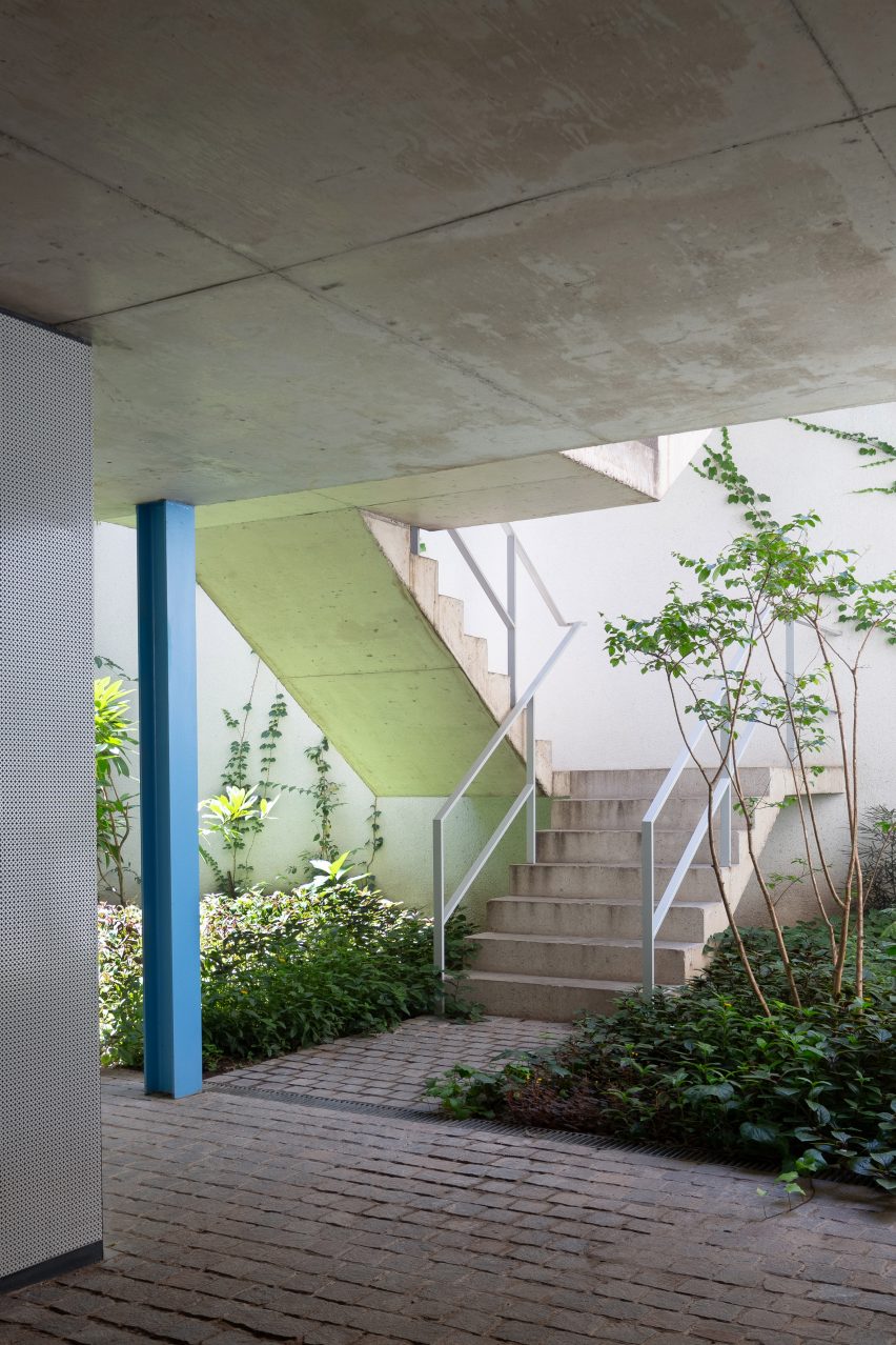 Concrete staircase in a courtyard supported by blue columns