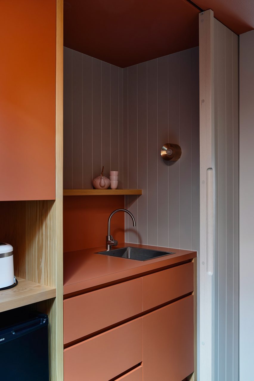 Kitchen with wood-lined walls and ochre units