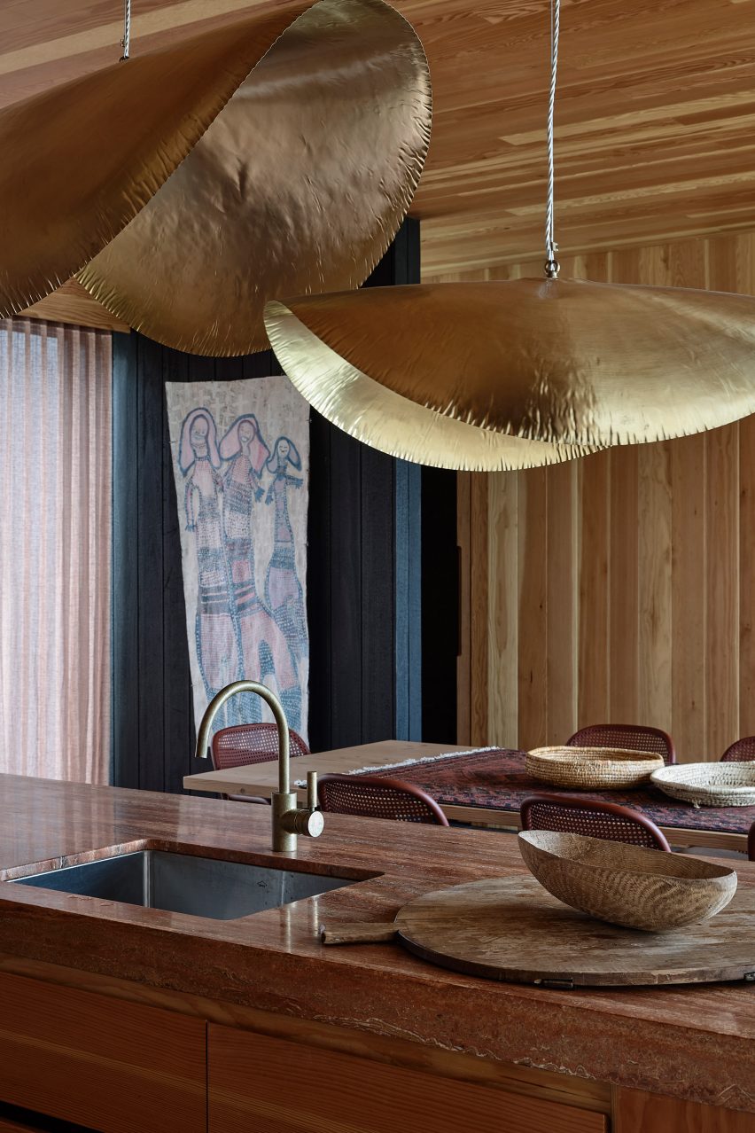 Kitchen with gold pendant light shades over a wood islands