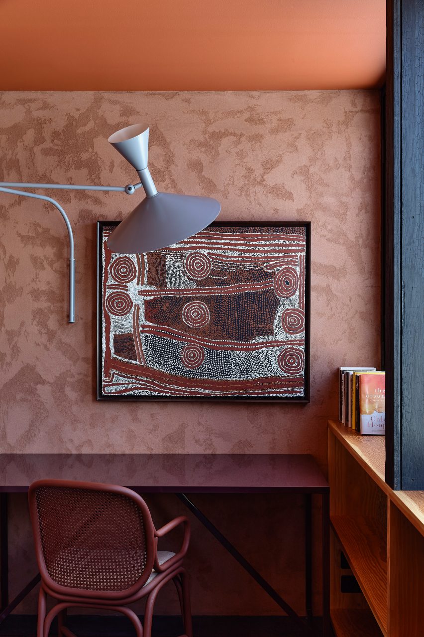 Maroon desk and chair in a pink-toned wallpapered room