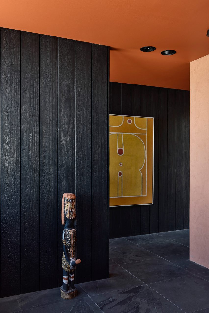 Interior room with terracotta-toned ceiling and blackened wood walls