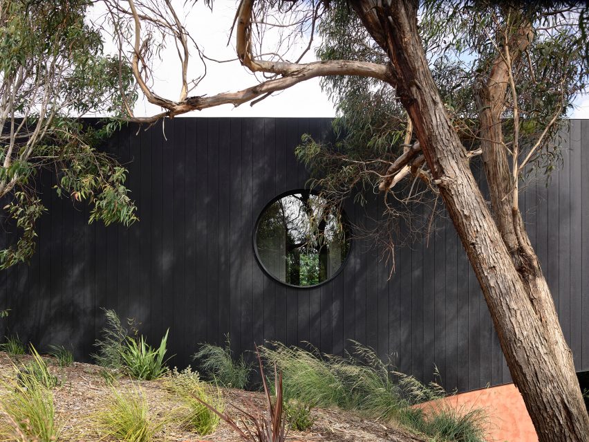 Charred timber exterior of Somers House with a circle window