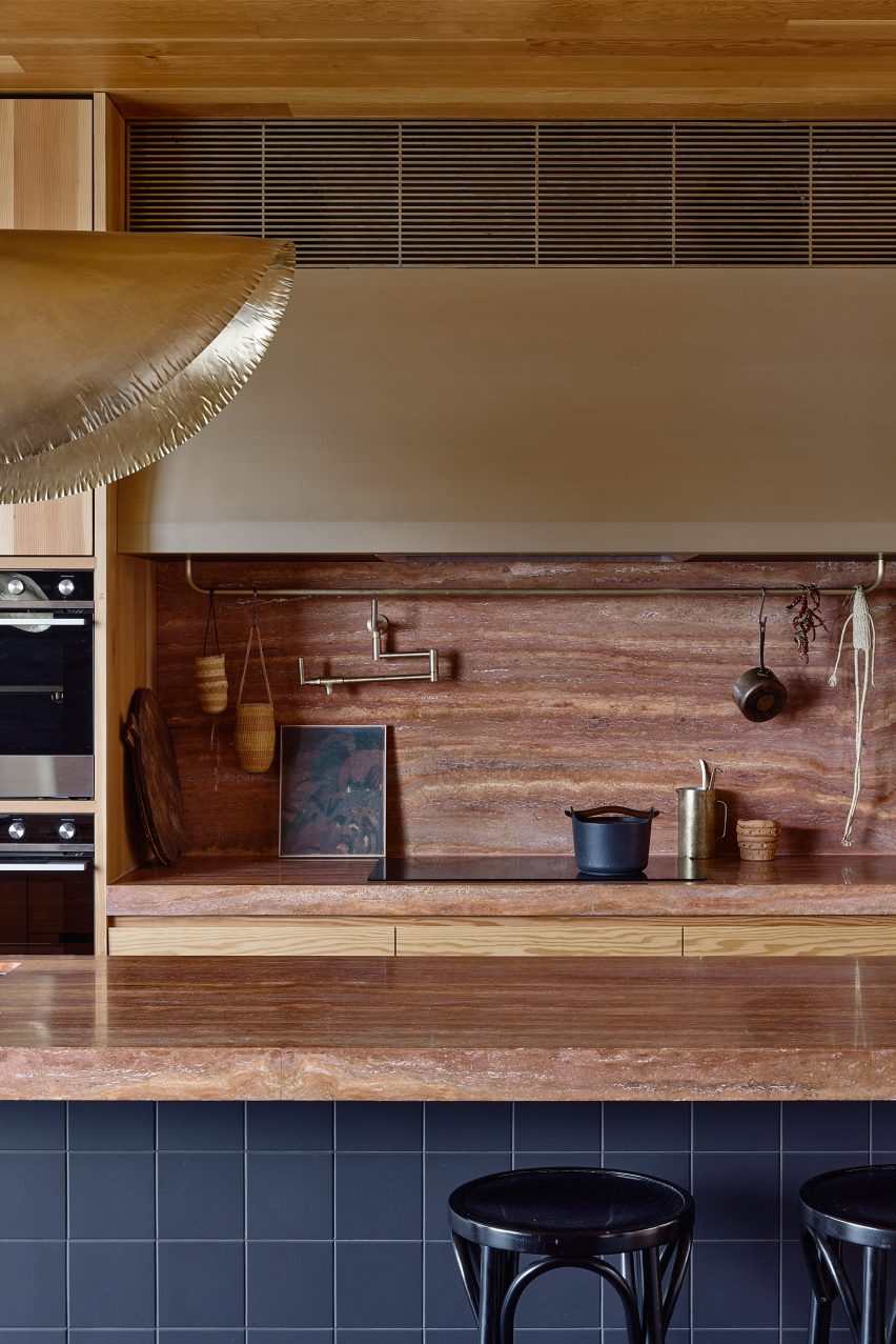Kitchen with wood units and island with dark grey tiled sides