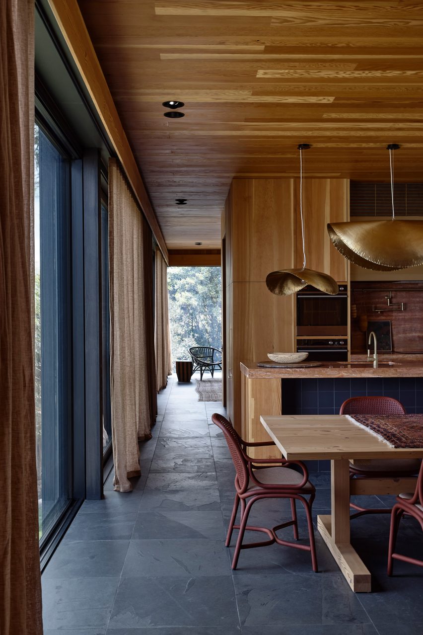 Timber-clad kitchen with wooden table and gold pendant lights