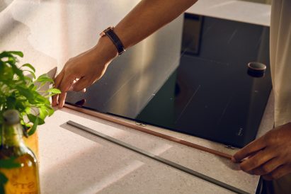 User sliding a bronze trim onto hob