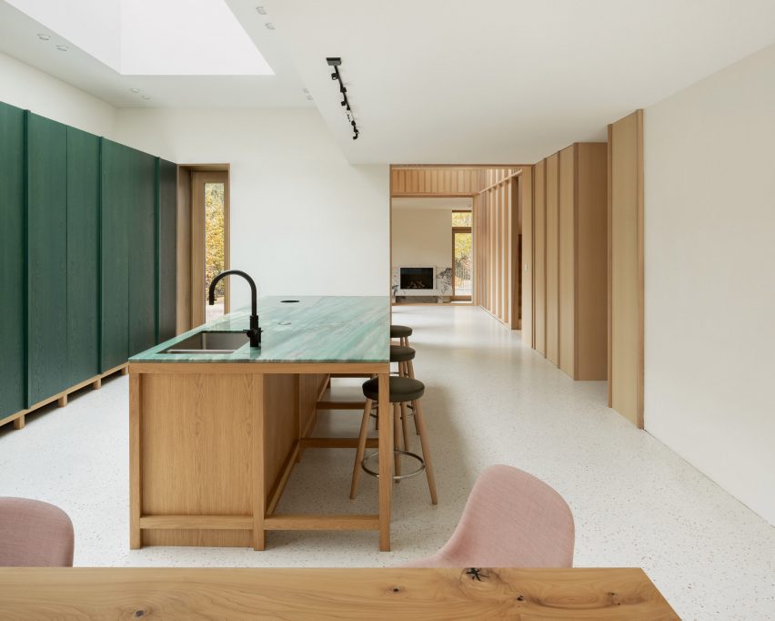 Kitchen with white walls and floors, green wall panels and a wood island