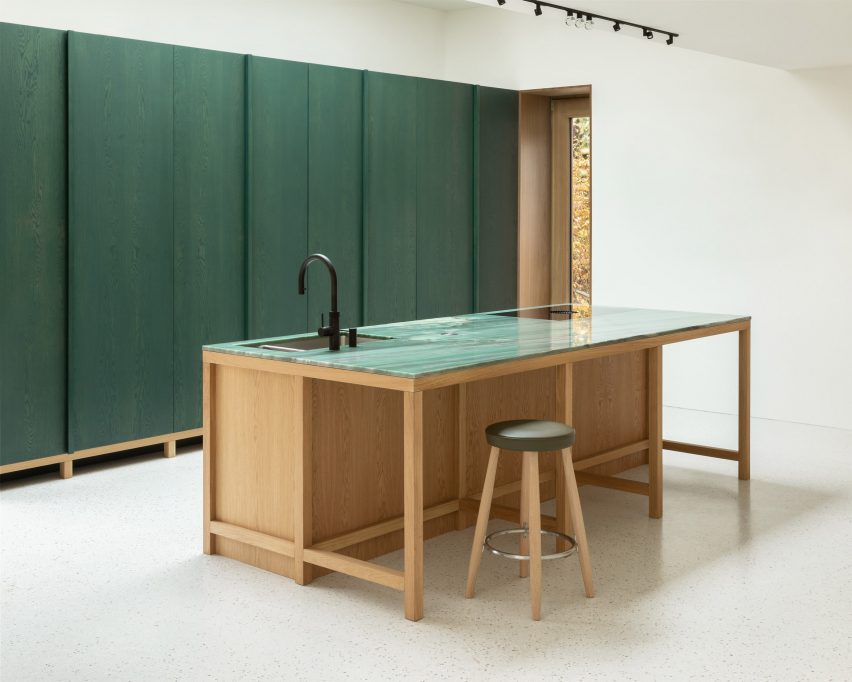 Kitchen with white walls and floors, green wall panels and wood kitchen island