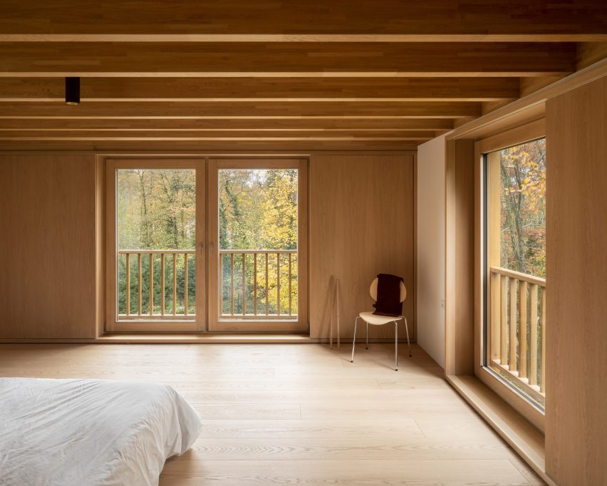 Timber-clad bedroom with windows overlooking a wooded area