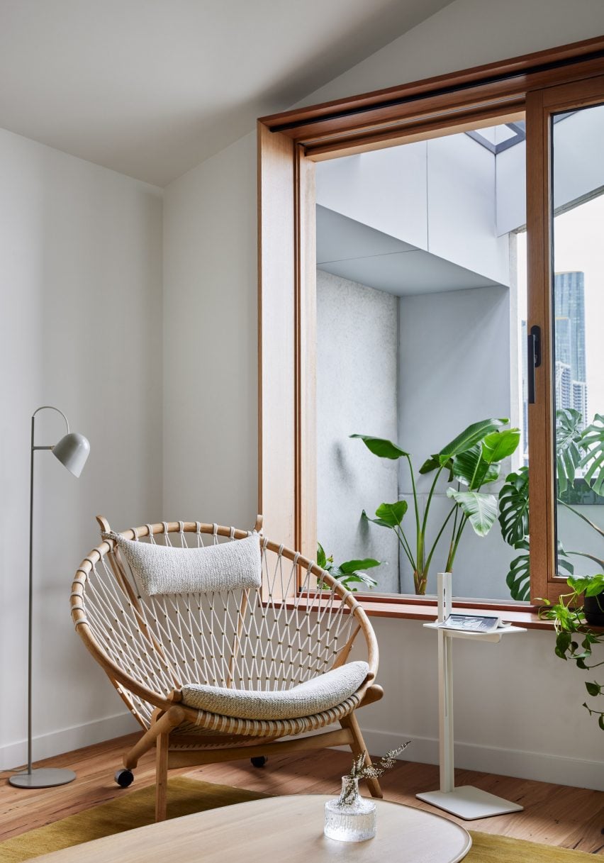 Lounge chair next to a wood-framed window overlooking a balcony