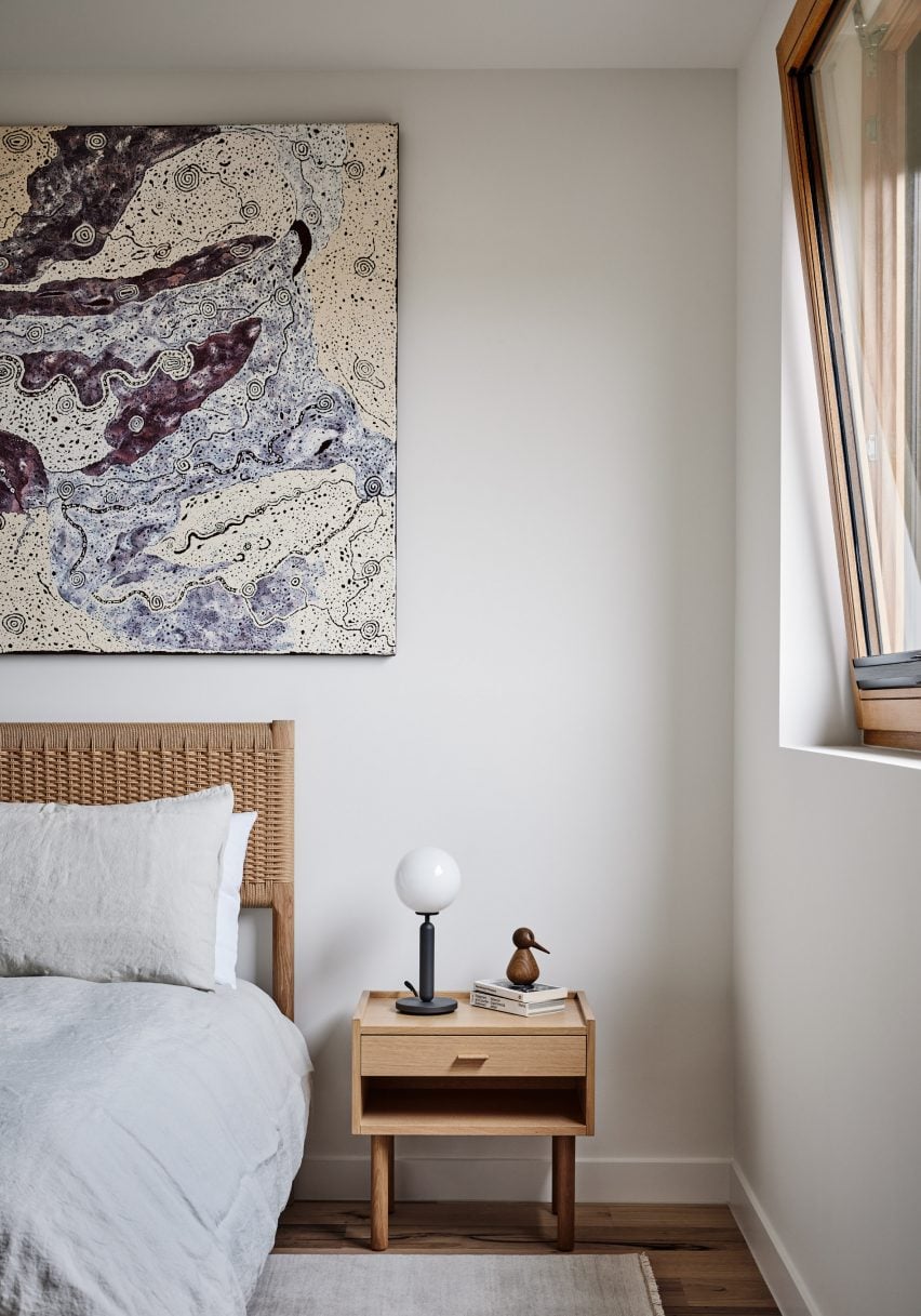 White bedroom with artwork and wooden bedside table