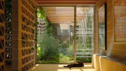 Yellow cushioned window seating nook with perforated breeze block walls by Architecture Architecture