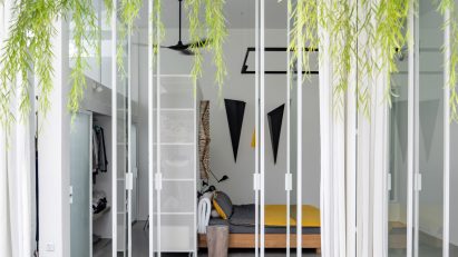 Courtyard with white-framed glass doors opening into a bedroom with hanging plants