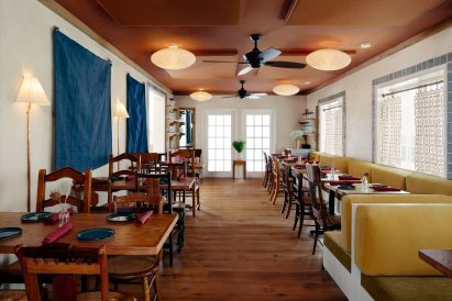Dining room with wooden furniture on the left and yellow banquettes to the right
