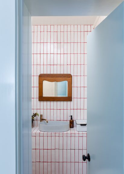White-tiled bathroom viewed through powder-blue door frame