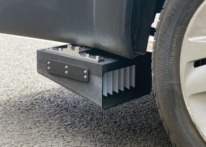 Photo of a box-like device mounted behind a wheel on a vehicle