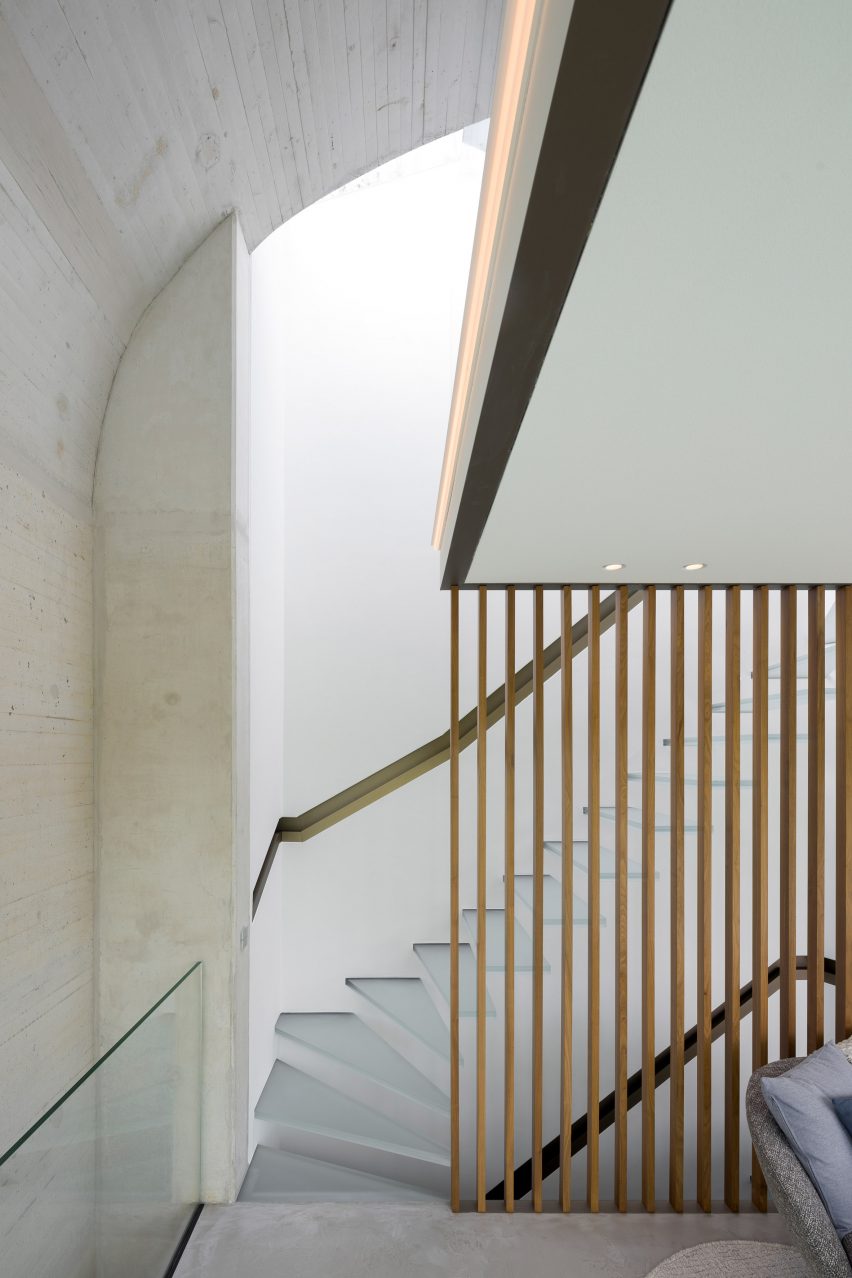 Frosted glass staircase in a concrete room with brass banister