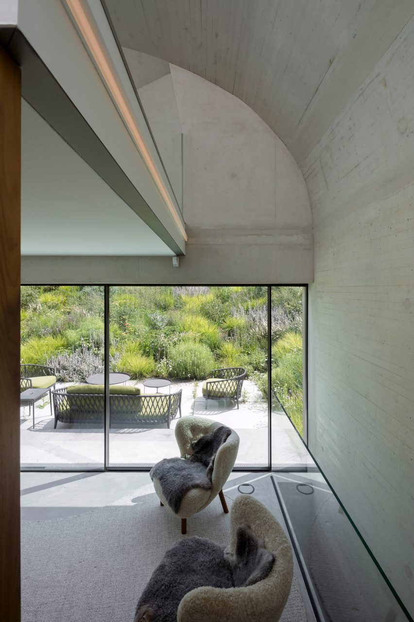 Concrete living space with lounge chairs and large glass doors leading to an outdoor terrace