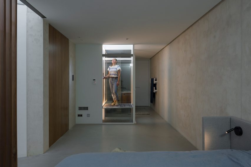 Concrete sunken room with a glass elevator