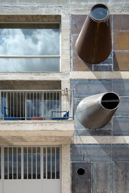 Photo of conical steel forms protruding from a building at odd angles to form a type of porthole window