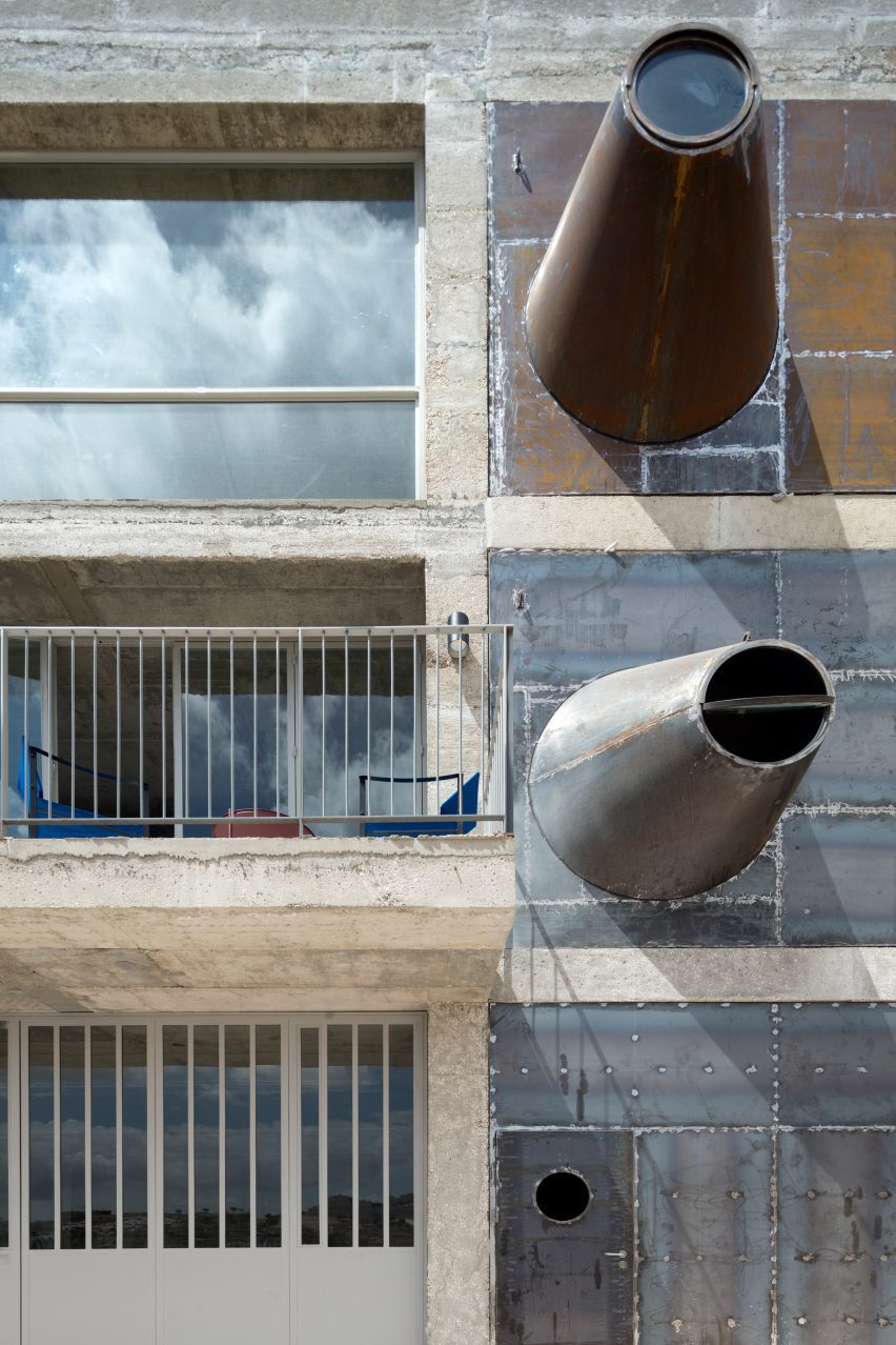 Photo of conical steel forms protruding from a building at odd angles to form a type of porthole window