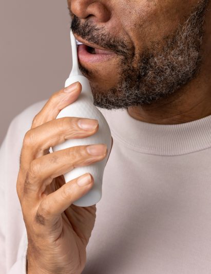 Photo of a man in close-up using an Access-ories toothbrush with a large, bulging handle to brush his teeth