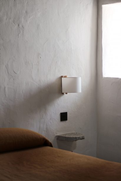 Close-up of rustic bedside table next to simple bed