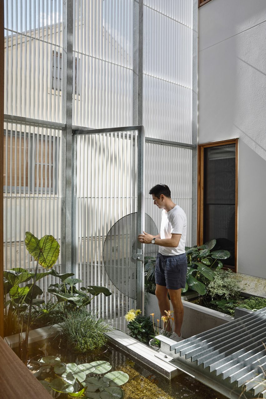 Person opening entrance gate leading to a pond in Melbourne house
