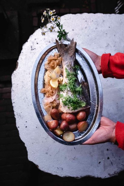 Hands serving a seabass dish