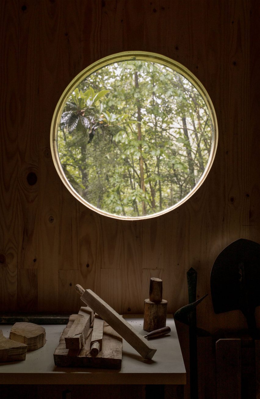 Circular window in a timber wall overlooking a forest