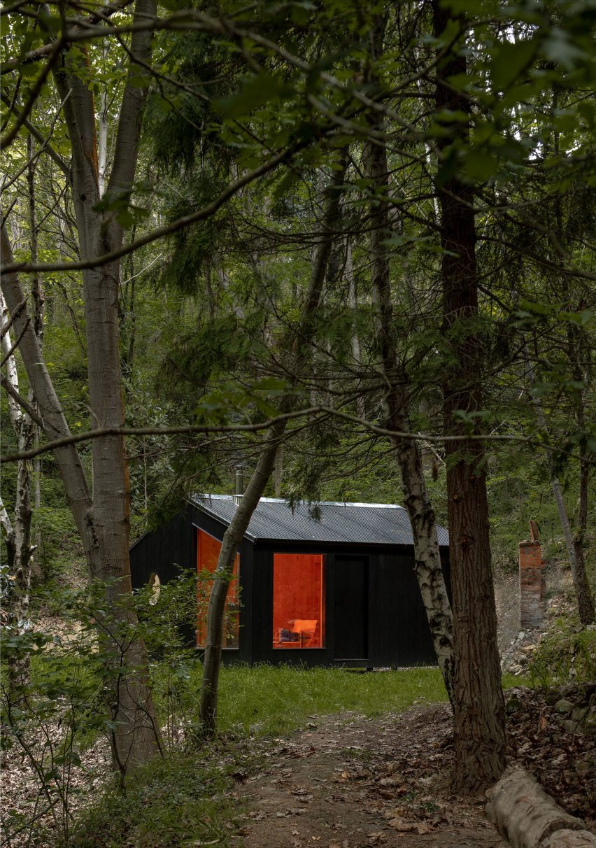 Black timber cabin in a forest by BABELStudio