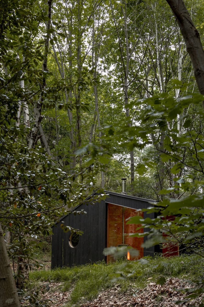 Black timber cabin in a forest by BABELStudio