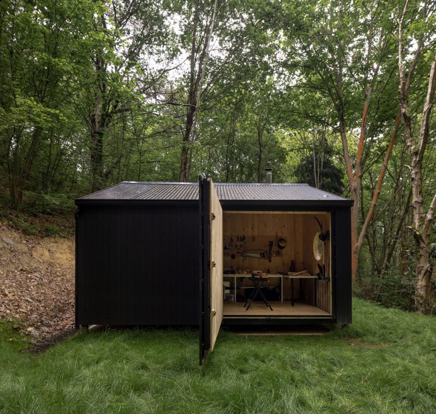 Black timber cabin in a forest by BABELStudio