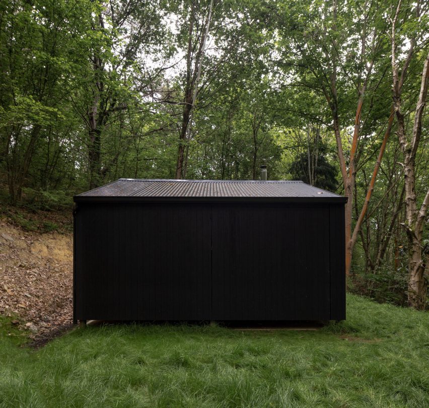 Black timber cabin in a forest by BABELStudio