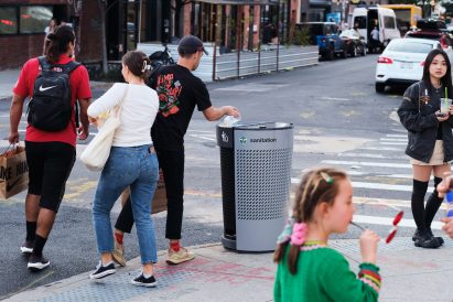 Person throwing away trash in gray waste bin