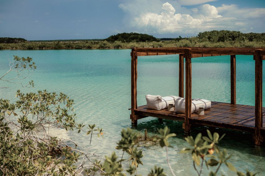a long dock made of dark wood with lounge cushions