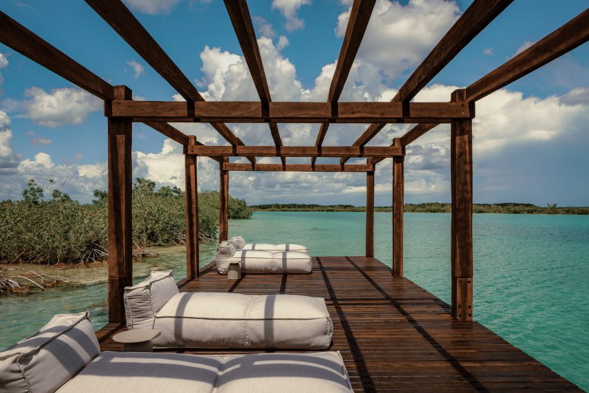a long dock made of dark wood with lounge cushions