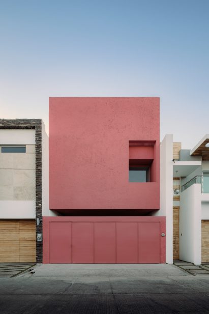 Street elevation of minimalist pink house between two white buildings