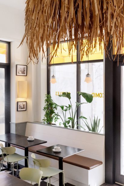Cafe tables sit below a raffia ceiling fixture