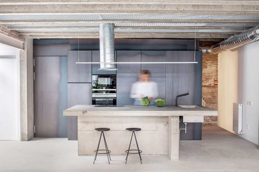 Kitchen with exposed ceiling beams and a concrete island