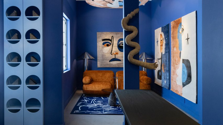 Photo of a living space with blue walls and rust-coloured art and sofa
