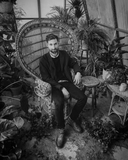 Person sitting in woven chair in greenhouse