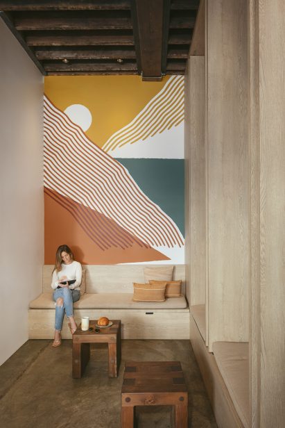 A woman sitting on a bench in front of a mural