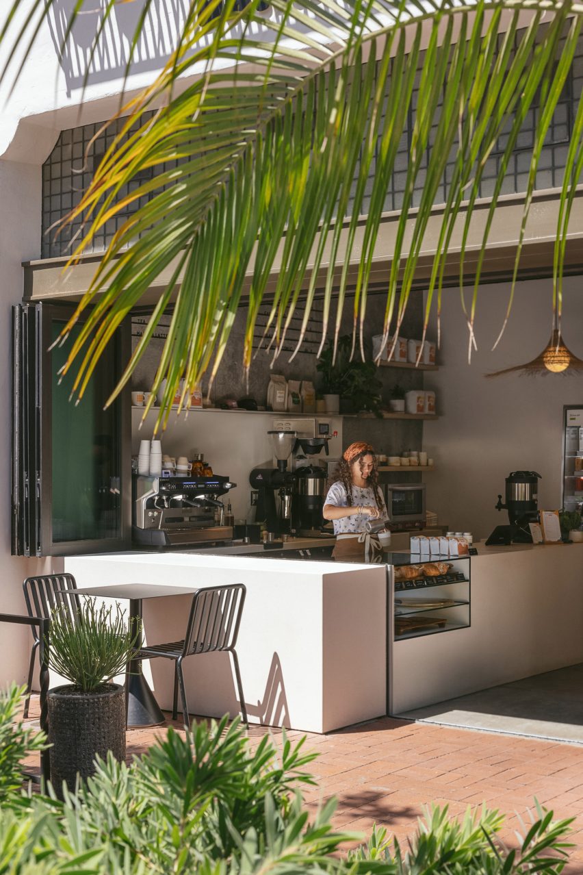 A woman pouring coffee at an indoor/outdoor cafe