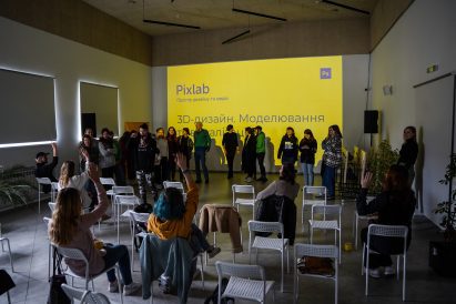 Photo of a gathering taking place in an event space at Pixlab in Lviv, with participants sitting in chairs raising their hands to ask questions